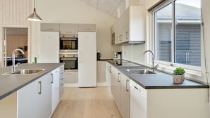 Une cuisine moderne dotée d’appareils électroménagers en acier inoxydable, d’une grande fenêtre et d’un design minimaliste.