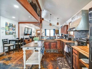 A spacious kitchen with a central island, wooden cabinets, and a built-in stove.