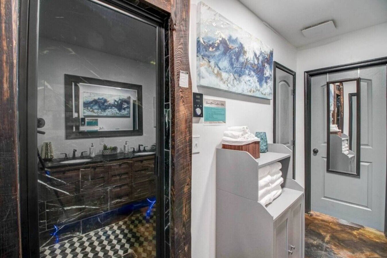 A bathroom with a large mirror, a sink, and a towel rack.