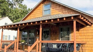 A wooden house with a porch, a staircase, and a garage door.