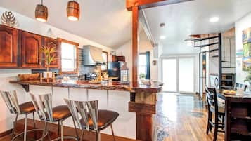A kitchen with a central island, bar stools, and a dining area with a table and chairs.