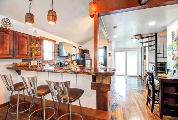 A kitchen with a central island, bar stools, and a dining area with a table and chairs.