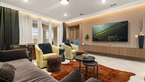 Un salon moderne doté d’un grand téléviseur à écran plat, de sièges confortables et offrant une vue sur l’extérieur.