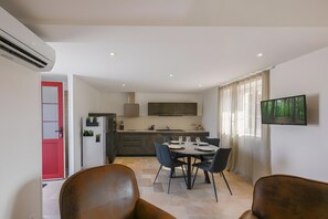 A modern kitchen with a dining area, a flat-screen TV, and a red door.