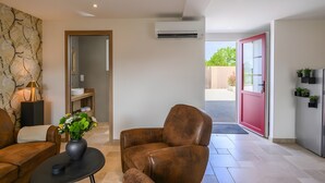 A modern living room with a brown leather sofa, a black coffee table, and a vase with flowers. - Holiday Home 'L'Ascalon' with Private Jacuzzi under Glass Dome, Wi-Fi & Air Conditioning (Saint-Sauveur-le-Vicomte)