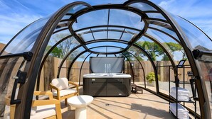 A hot tub under a glass dome structure with a sofa and a small table. - Holiday Home 'L'Ascalon' with Private Jacuzzi under Glass Dome, Wi-Fi & Air Conditioning (Saint-Sauveur-le-Vicomte)
