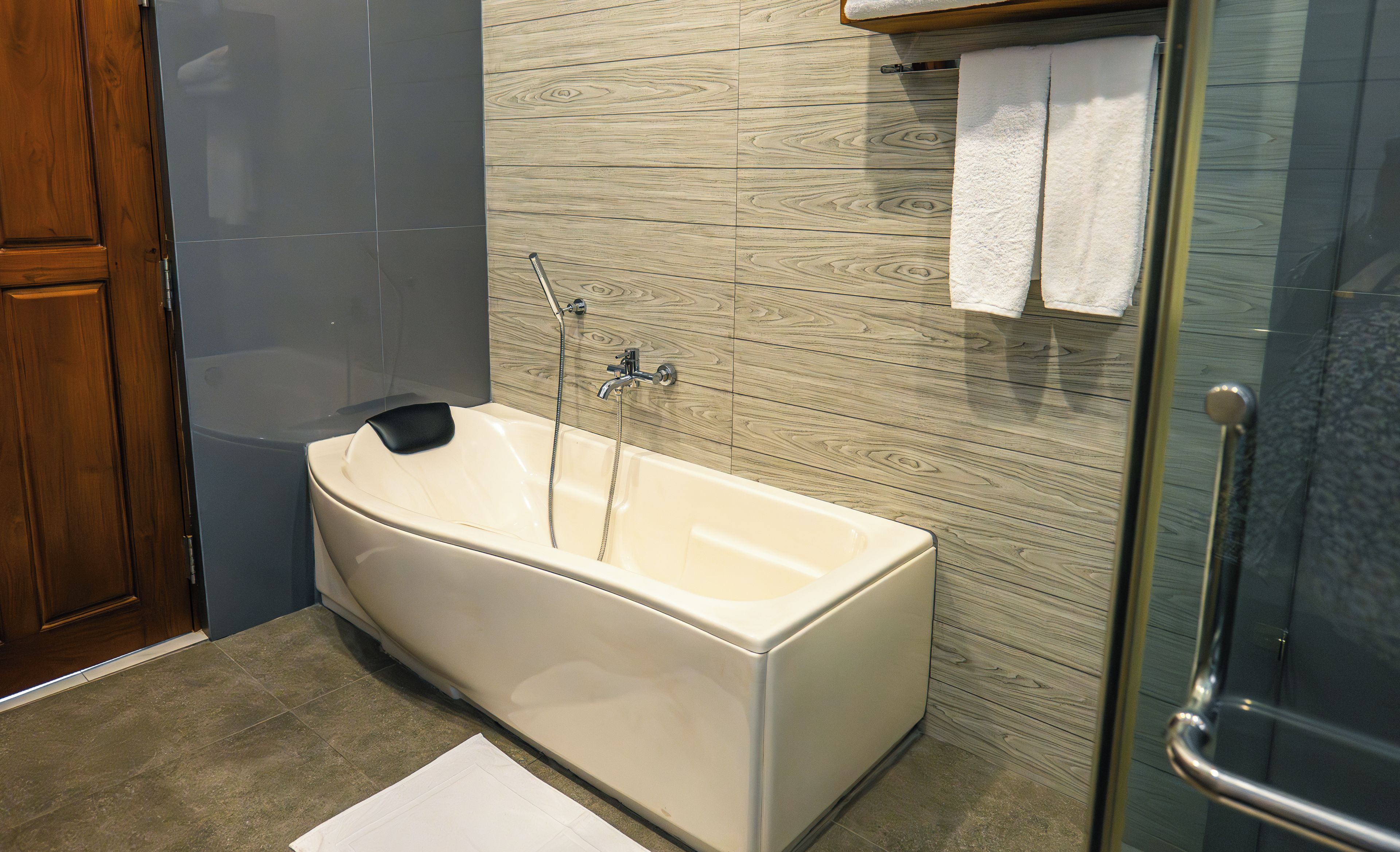A bathroom with a bathtub, a shower, and a wooden wall.