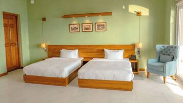 Une chambre d’hôtel avec deux lits en bois, une chaise, une table de chevet avec un téléphone et des tableaux accrochés au mur.