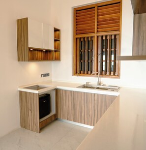 A kitchen with a built-in dishwasher, a sink, and wooden cabinetry. - At Kelly's Ambalangoda (Ambalangoda)