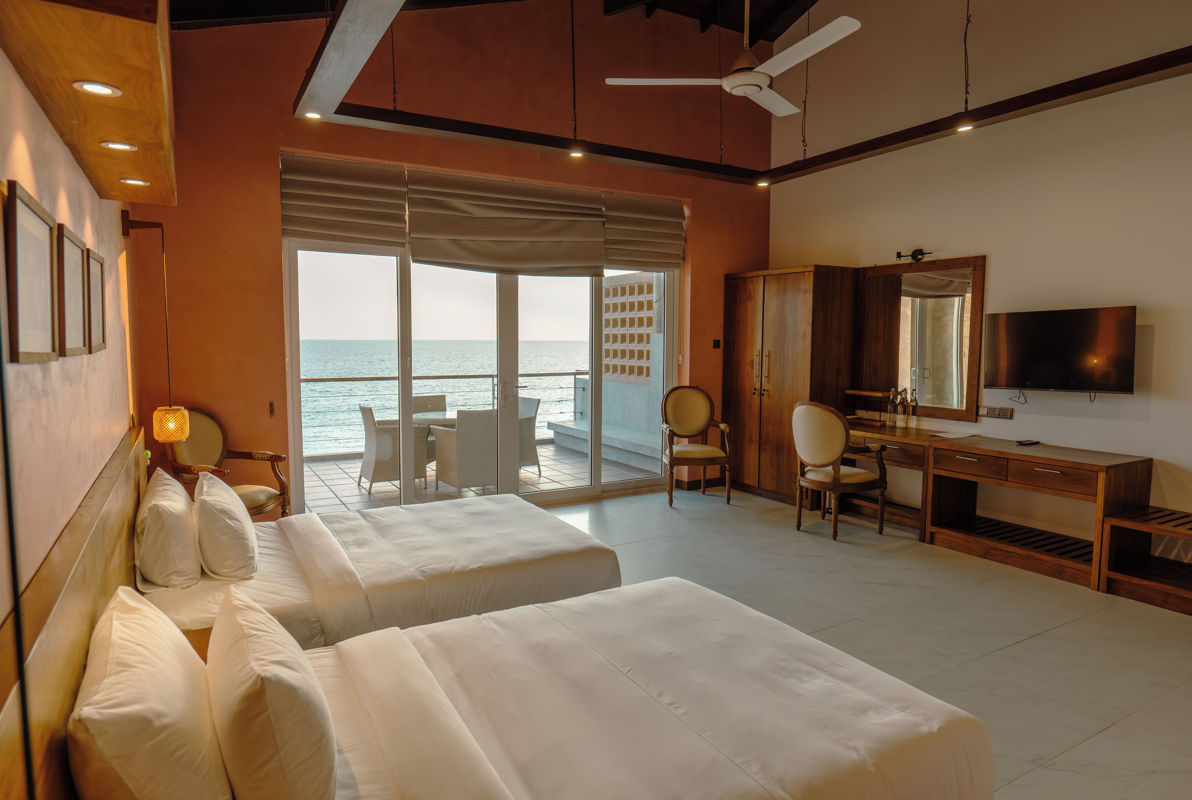Una camera d'albergo con due letti, una scrivania, una televisione e vista mare.