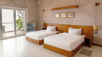 A hotel room with two beds, a chair, a balcony, and a wall-mounted shelf with pictures.