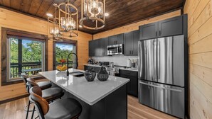A modern kitchen with a central island, stainless steel appliances, and wooden paneling. - Rooftop Hot Tub, Indoor Pool, Sunrise & Mtn Views (Pigeon Forge)