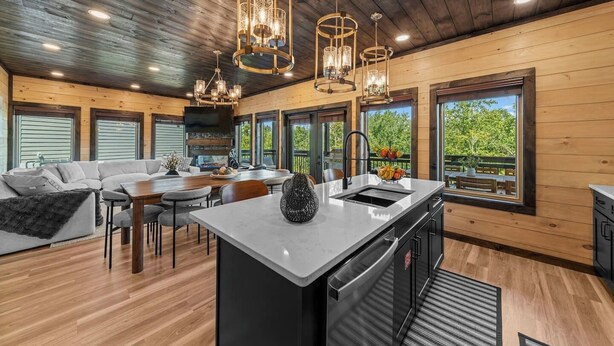 A spacious kitchen with a central island, wooden ceiling, and large windows offering views of greenery. - Rooftop Hot Tub, Indoor Pool, Sunrise & Mtn Views (Pigeon Forge)