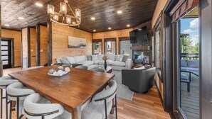 A spacious living area with a wooden ceiling, a large wooden dining table, and a comfortable seating arrangement. - Rooftop Hot Tub, Indoor Pool, Sunrise & Mtn Views (Pigeon Forge)