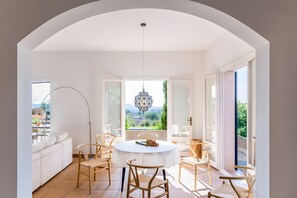 Un coin repas avec une table ronde, une nappe blanche et des chaises en bois.
