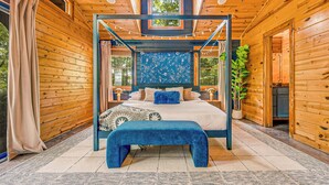 Une chambre à coucher dans un chalet en bois, avec un lit à baldaquin, un banc et une vue sur l’extérieur.