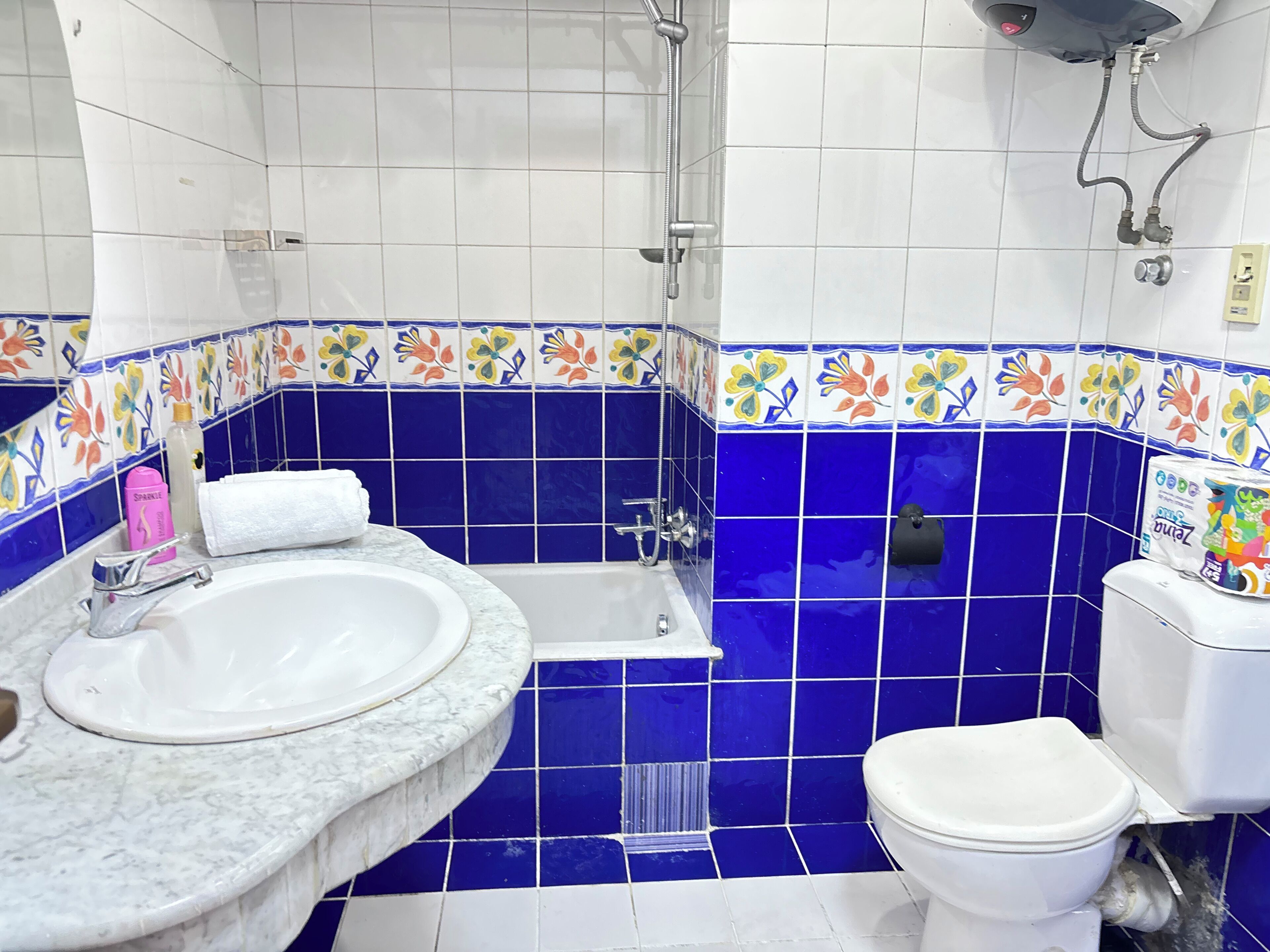 A bathroom with a sink, bathtub, and toilet, featuring blue and white tiles with floral patterns.