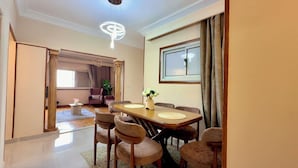 A dining area with a wooden table and chairs, a vase with flowers, and a modern chandelier. - Golden mile - Downtown Cairo (Cairo)