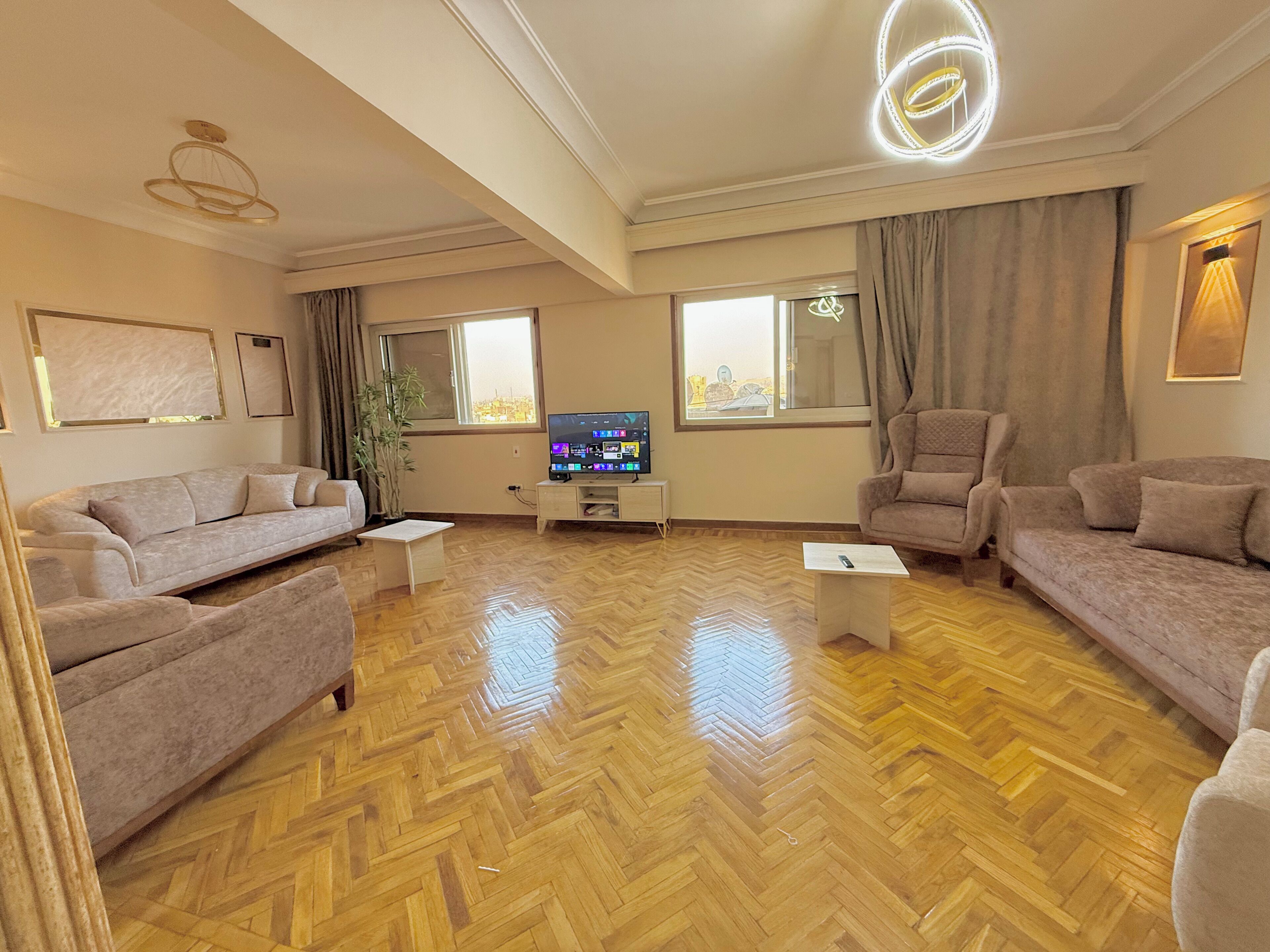 Un salon spacieux doté d’un parquet en bois disposé en point de Hongrie, de deux canapés, d’une table basse et d’un téléviseur.