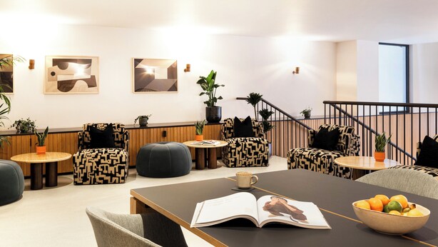 Ein moderner Lounge-Bereich mit gemusterten Sitzgelegenheiten, einem Couchtisch und einer Schale mit Obst.