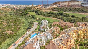Un resort costero con piscina, varias edificaciones y vista al mar.