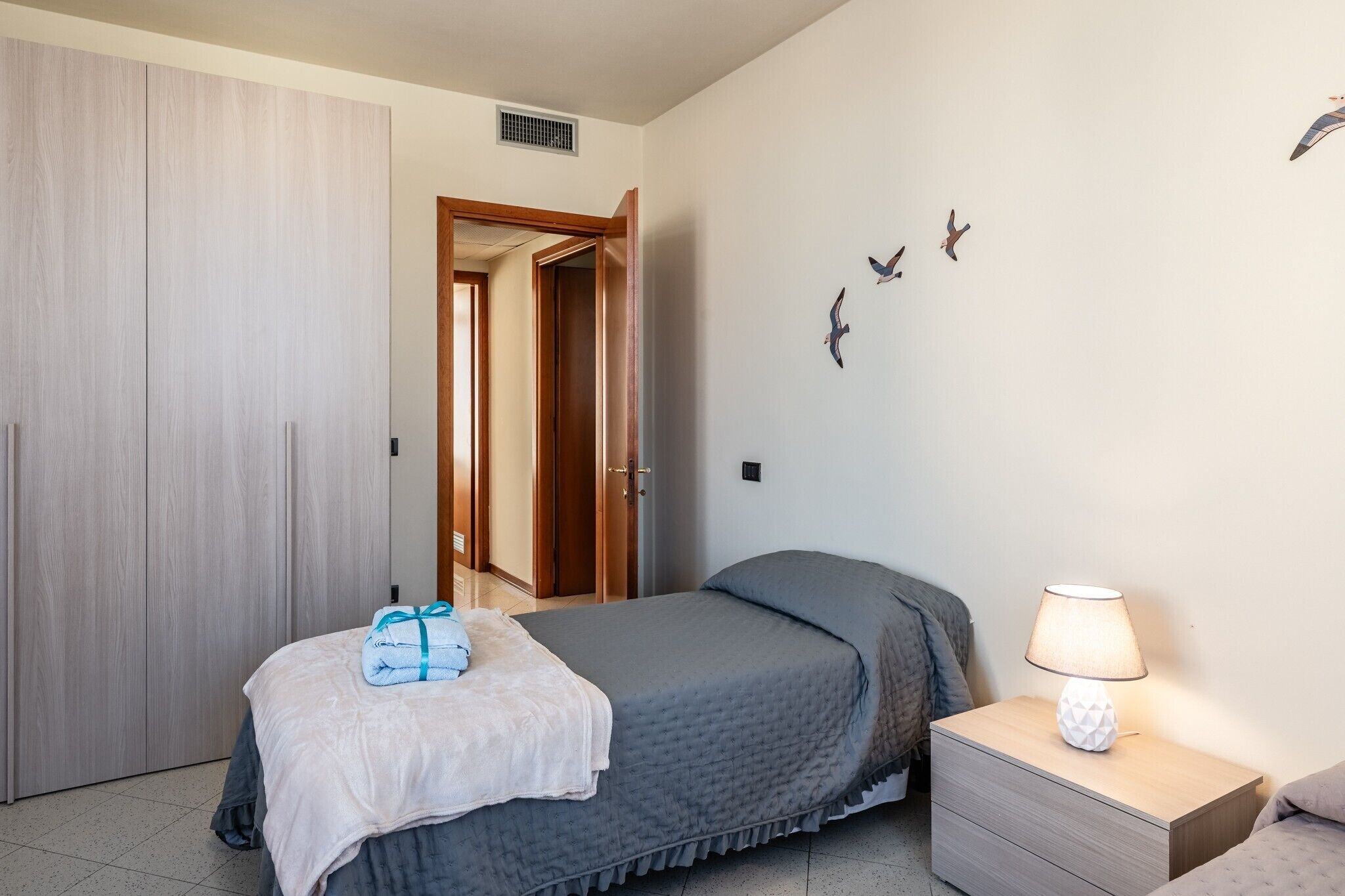 A bedroom with a bed, bedside lamp, and a wardrobe.