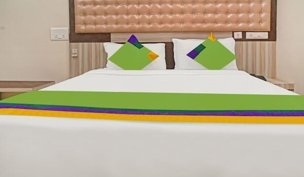 A bed with a green and purple bedspread, a tufted headboard, and two pillows with geometric patterns. - HOTEL JSN GRAND (Vijayawada)