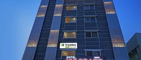 Un edificio de varios pisos con un letrero que dice 'Treebo JSN Grand Luxury Rooms'.
