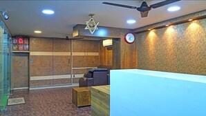 A reception area with a reception desk, seating area, and a wall-mounted clock. - HOTEL JSN GRAND (Vijayawada)