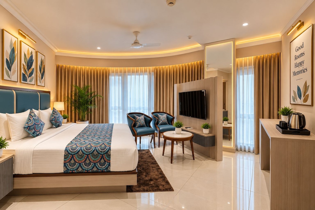 A modern hotel room with a bed, seating area, TV, and a desk.