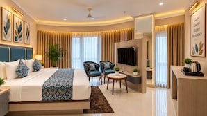 Habitación de hotel moderna con cama, zona de estar, televisor y escritorio.