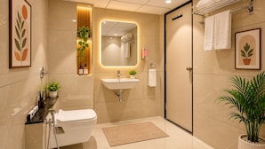 Un baño moderno con inodoro, lavabo y ducha. Hay plantas y un espejo en la pared.