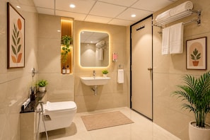A modern bathroom with a toilet, sink, and shower. There are plants and a mirror on the wall. - Hotel Royal Time (Ahmedabad)
