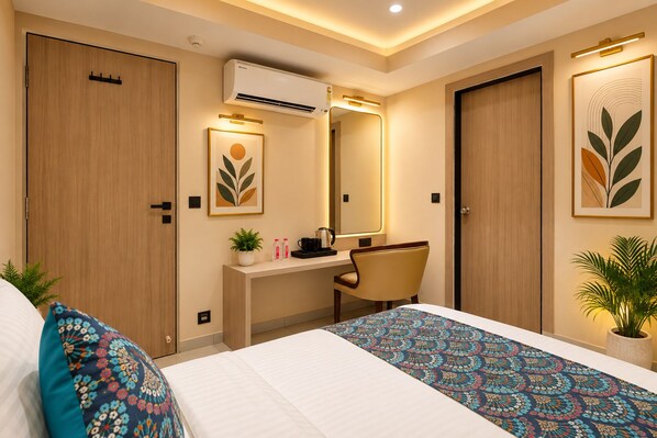 Habitación de hotel con cama, escritorio, silla, espejo y una planta en maceta.