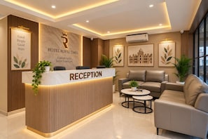 A hotel reception area with a reception desk, seating area, and artwork on the walls. - Hotel Royal Time (Ahmedabad)