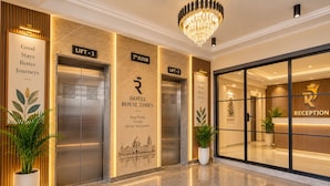 Un vestíbulo de hotel con dos ascensores, una recepción y un candelabro.
