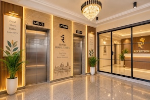 A hotel lobby with two elevators, a reception desk, and a chandelier. - Hotel Royal Time (Ahmedabad)