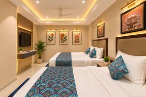Habitación de hotel con dos camas, televisión de pantalla plana, obra de arte en la pared y ventilador de techo.