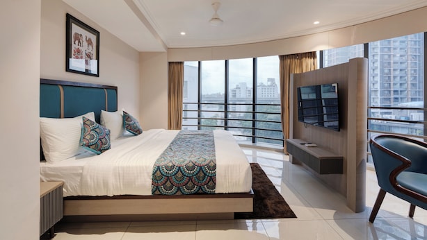 Un dormitorio moderno con una cama grande, televisión y vista a la ciudad.