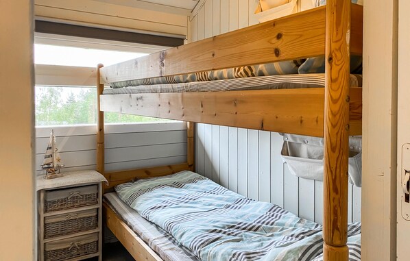 A bunk bed with a lower bunk and a single bed, wooden headboard, and a small shelf with baskets.