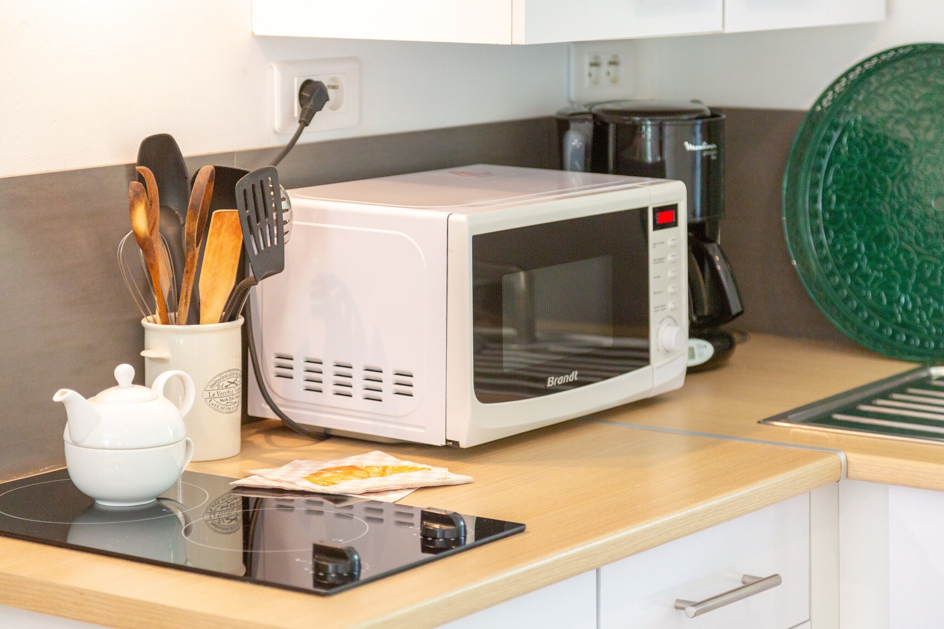 Een keuken met een magnetron, koffiezetapparaat en keukengerei.