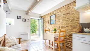 Une pièce chaleureuse avec un mur en pierre, une table à manger avec des chaises, un banc et un petit coin cuisine.