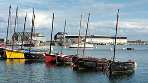 Un port de plaisance avec plusieurs bateaux amarrés, un bâtiment en arrière-plan et une eau calme.