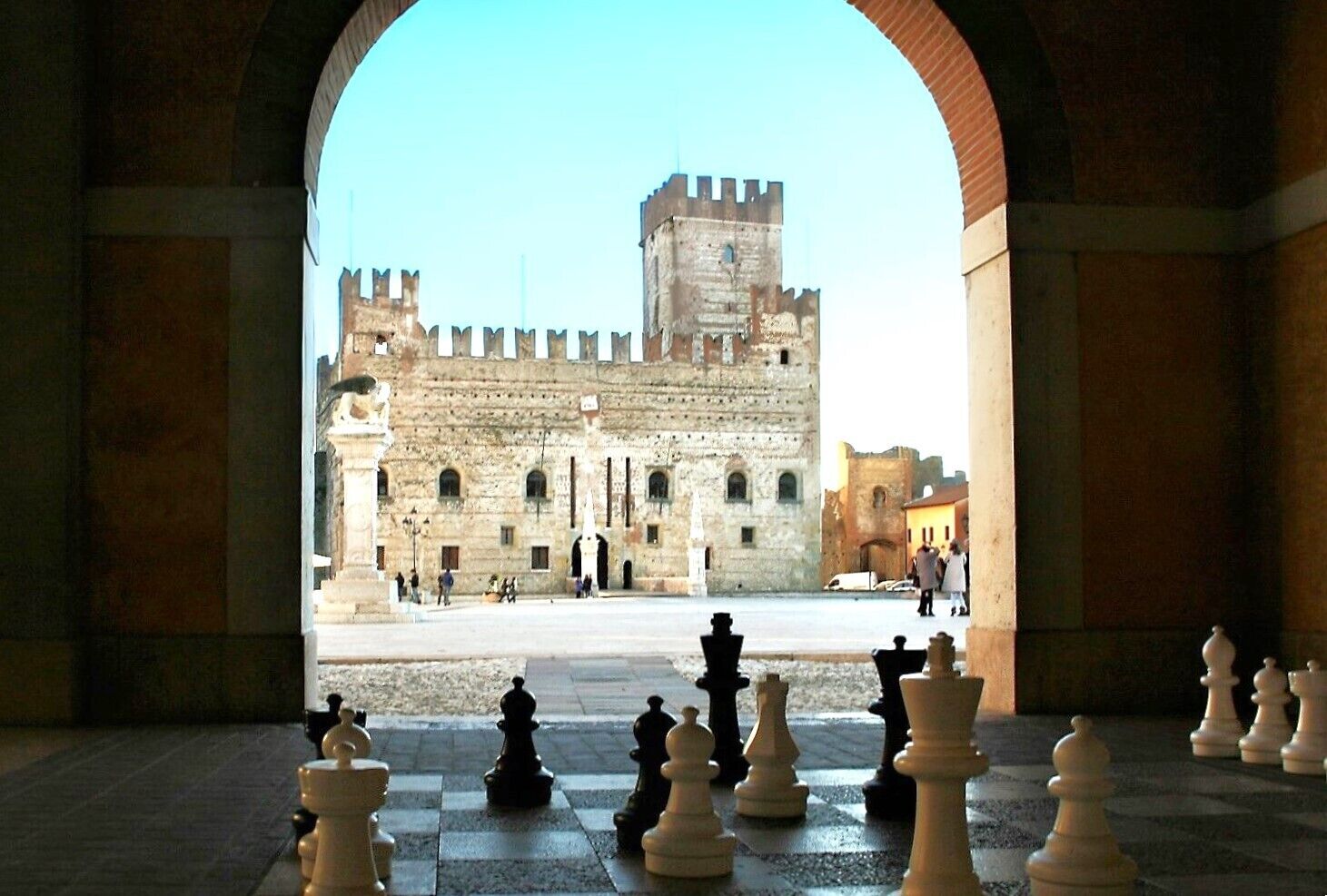 A view of a historic building with a large open courtyard and a chessboard in the foreground.