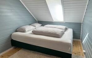 A bedroom with a sloped ceiling, a bed with white bedding, and a skylight. - Amazing apartment in Arendal with WiFi (Arendal)