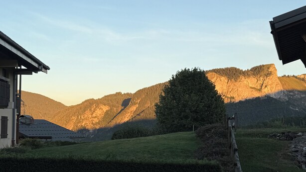 A residential area with a house, a well-maintained lawn, and a mountain backdrop.
