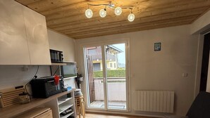 A compact kitchen with wooden cabinets, a microwave, and a toaster. There is a sliding glass door leading to an outdoor area.