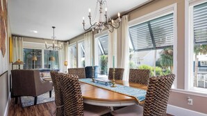 A dining area with a wooden table, woven chairs, and a chandelier.
