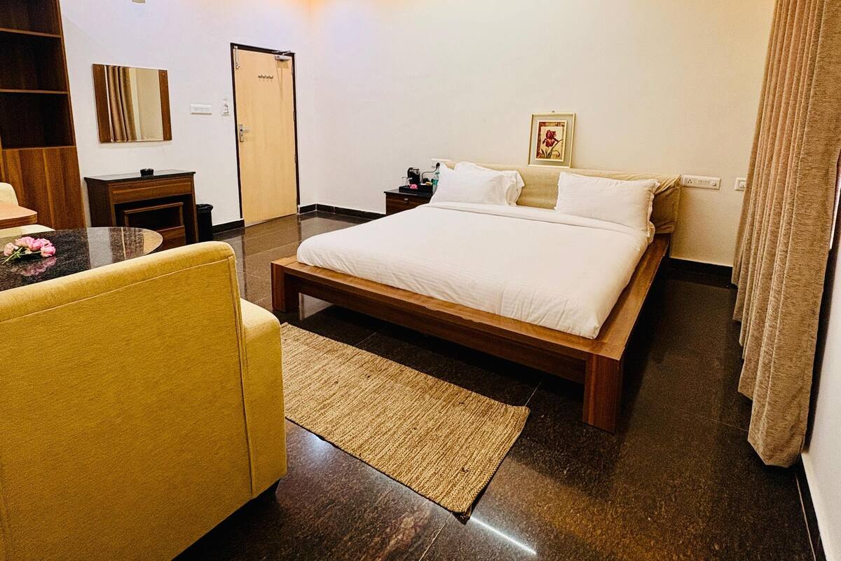 A modern hotel room with a large bed, a desk, a chair, and a ceiling fan.
