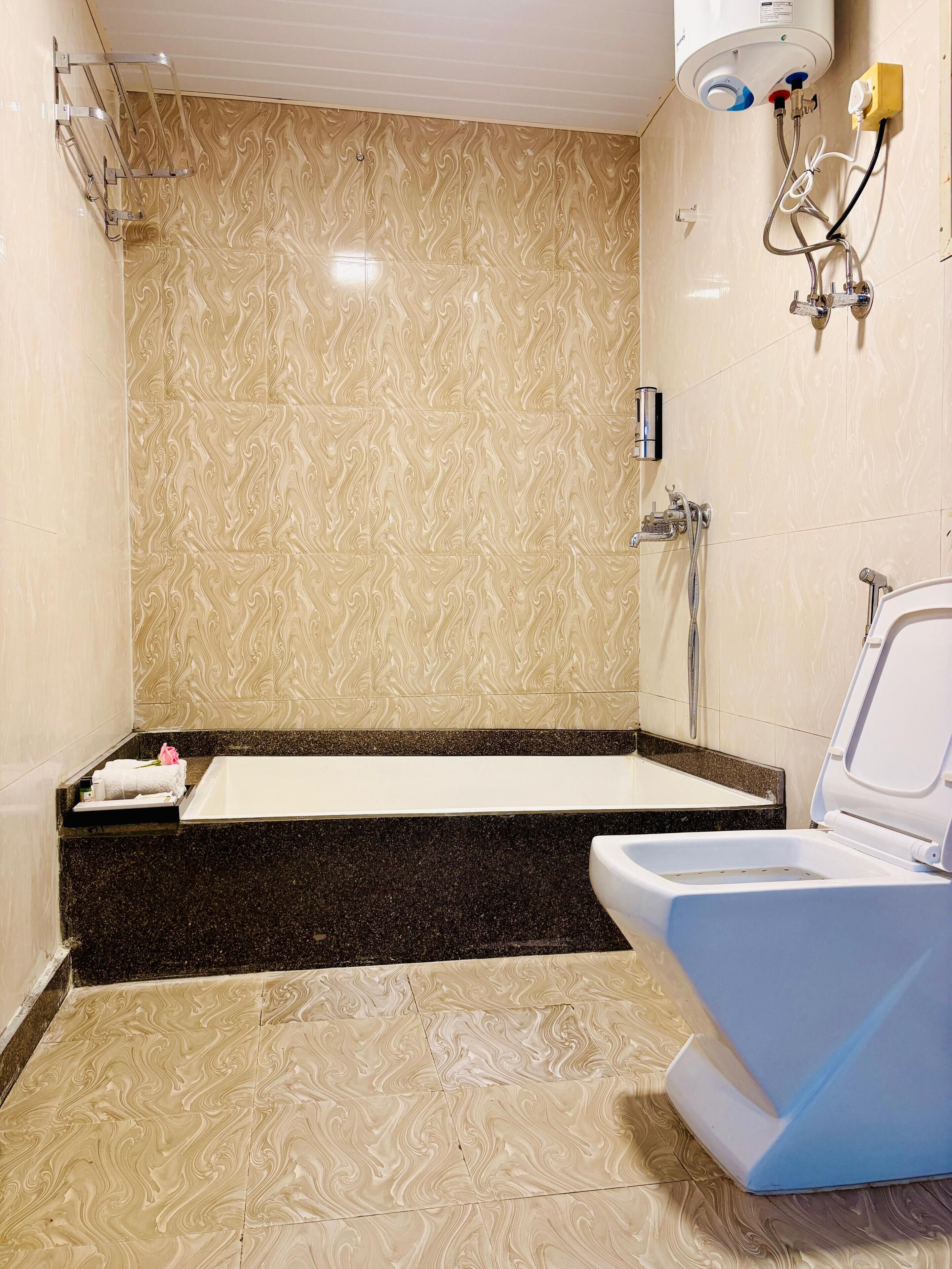 A bathroom with a marble wall, a bathtub, a shower, and a toilet.
